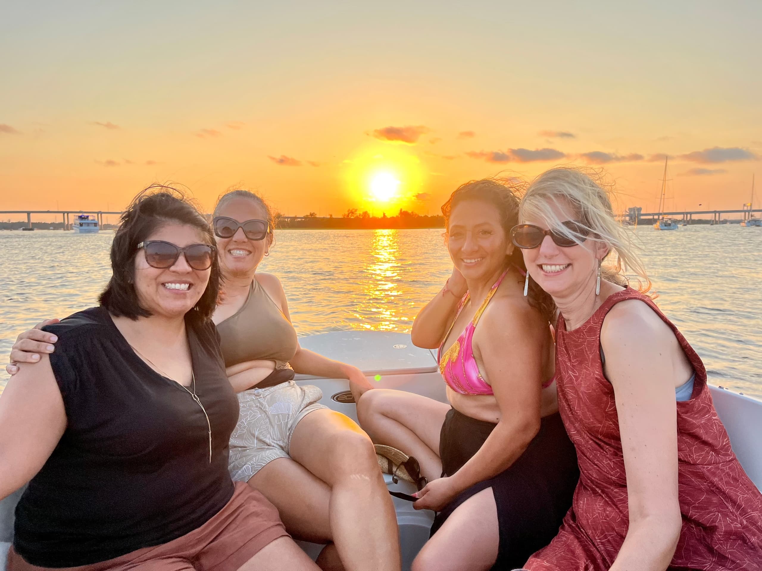 Friends enjoying sunset boat cruise over water with skyline