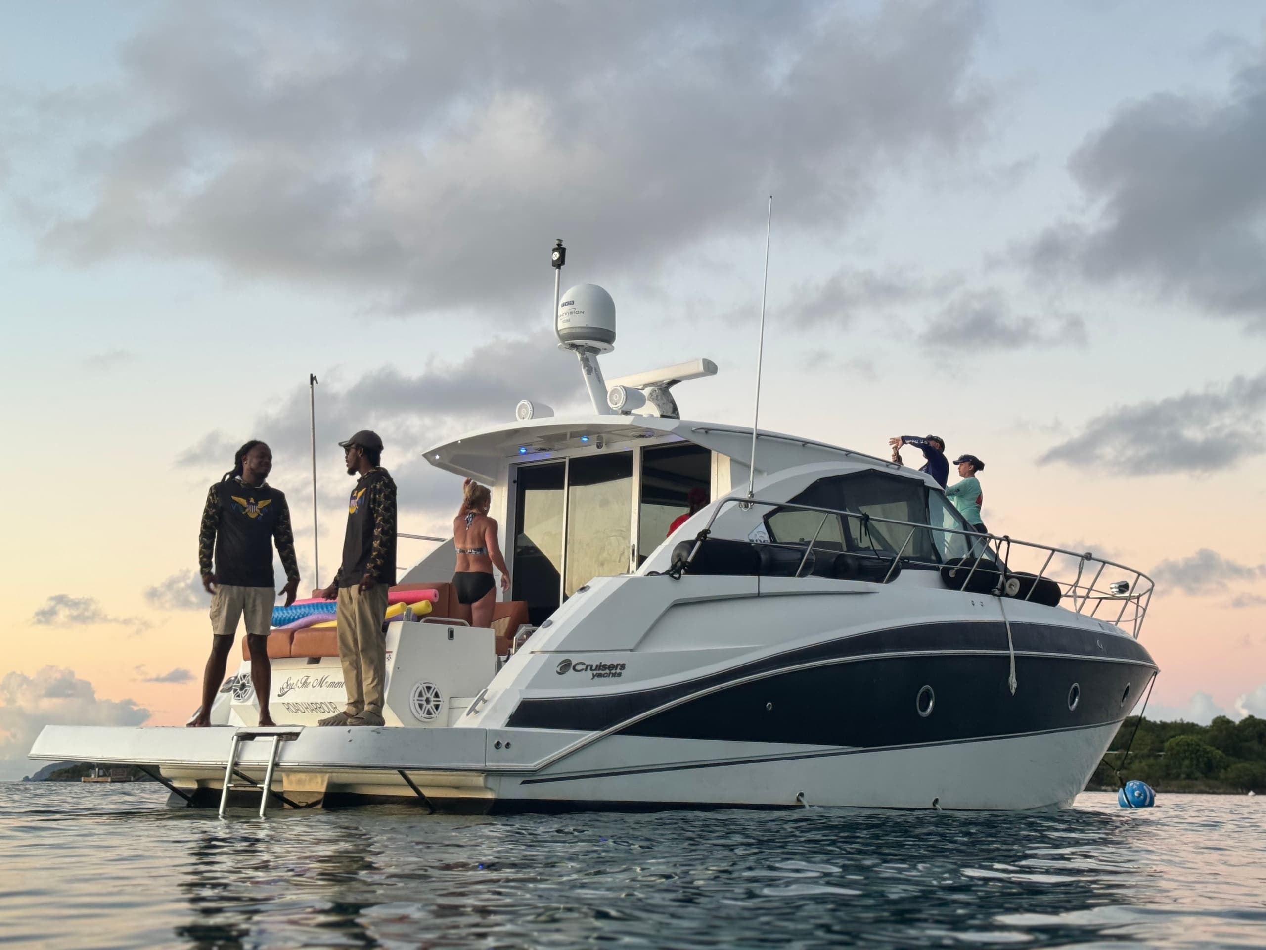 Motorboat anchored at sunset with passengers on stern near shore