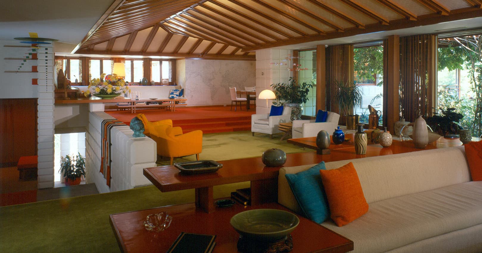 Spacious midcentury living room with panoramic windows and garden views