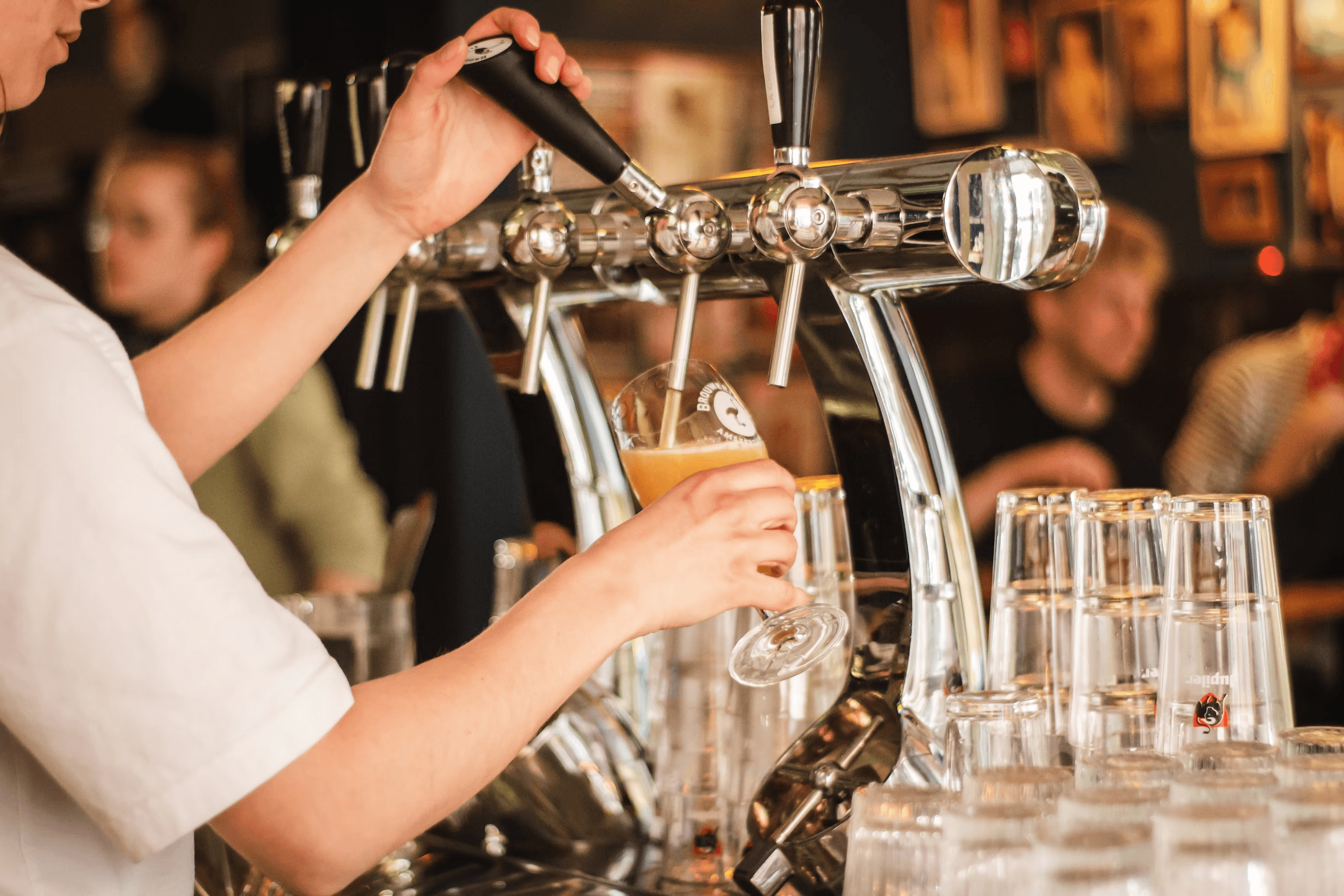 Bartender pouring draft beer at indoor pub bar counter