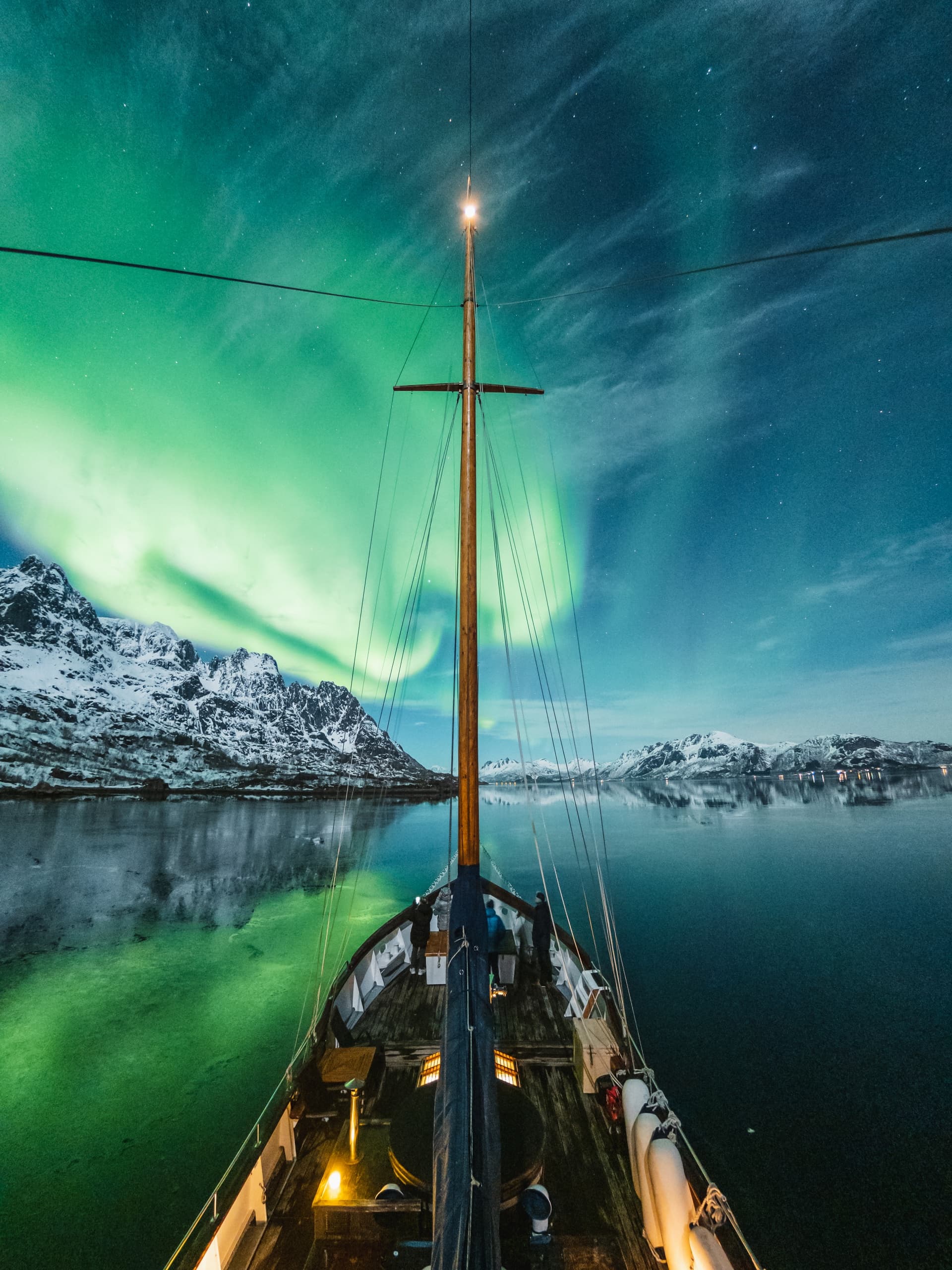 Sailboat under vivid northern lights above icy Arctic waters