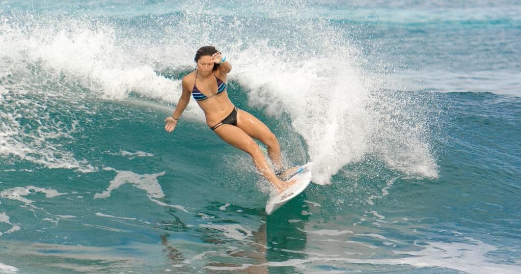 Female surfer carving a turquoise wave during surf lesson