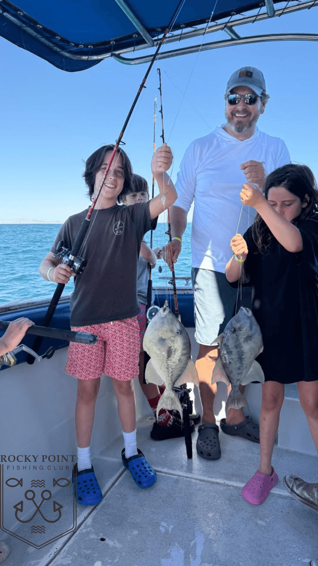 Family fishing charter aboard boat holding freshly caught fish