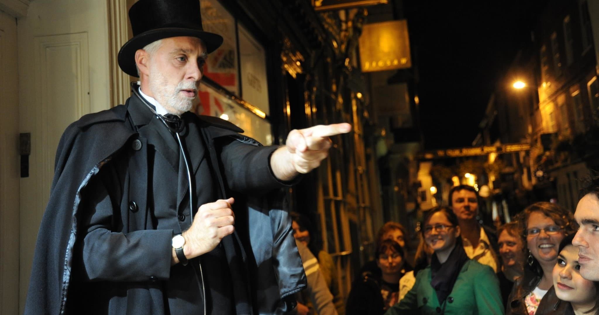 Guide leading nighttime ghost walking tour on historic city street