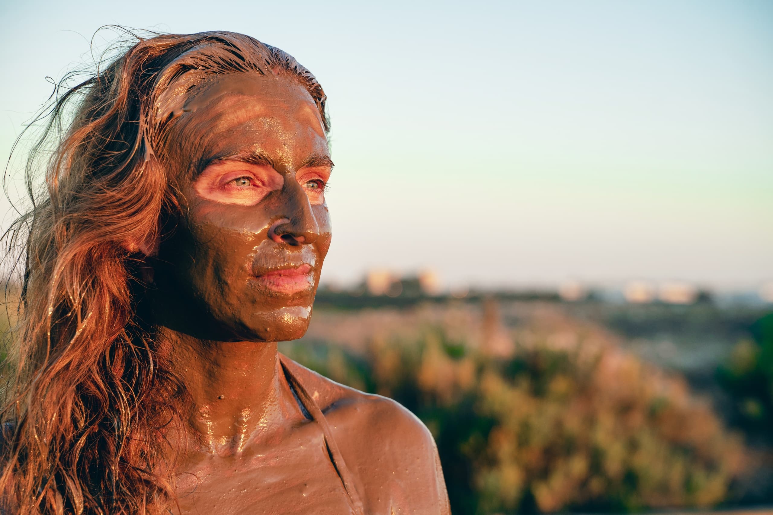 Woman with therapeutic mud face mask outdoors on salt flats