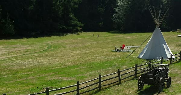 Tipi on open grassy field with picnic table at ranch campground