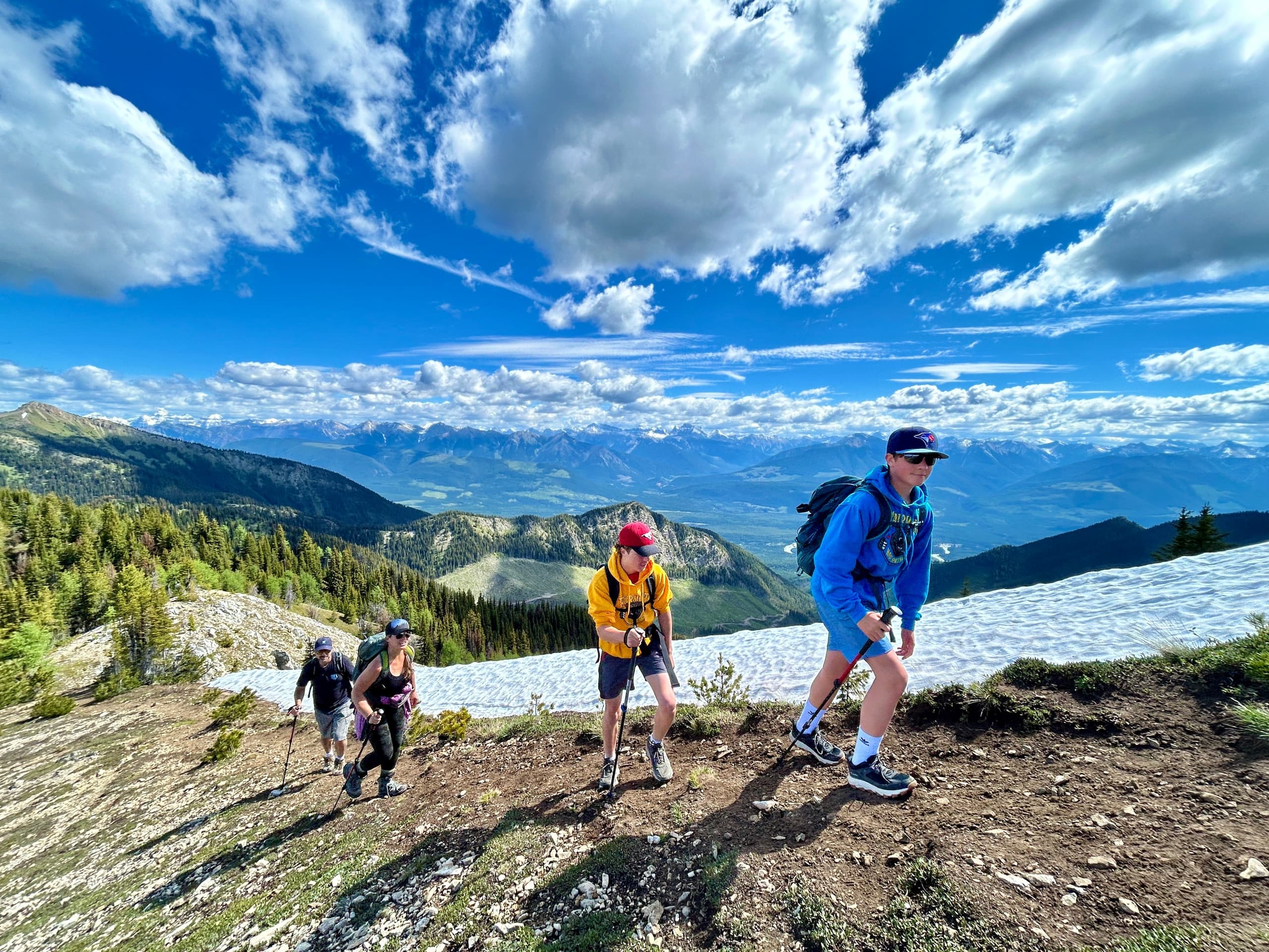 Trail runners ascending alpine ridge with dramatic cloudscape