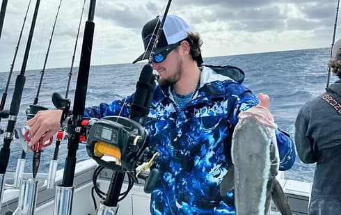 Angler holding caught fish aboard offshore sportfishing boat