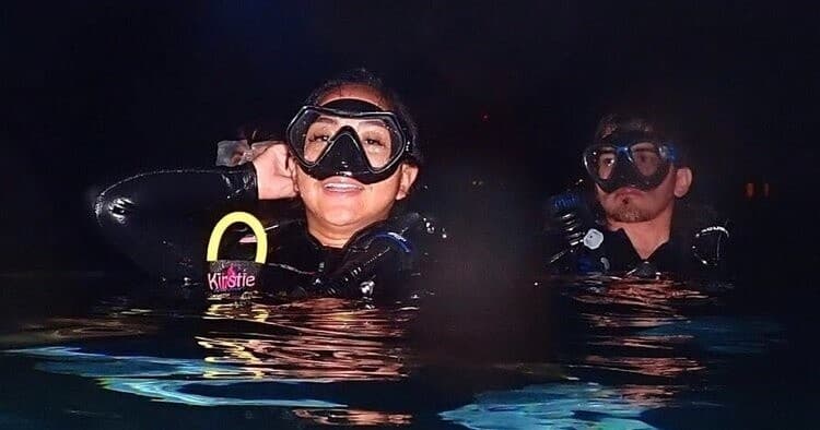 Night scuba divers at surface in open ocean prepping gear