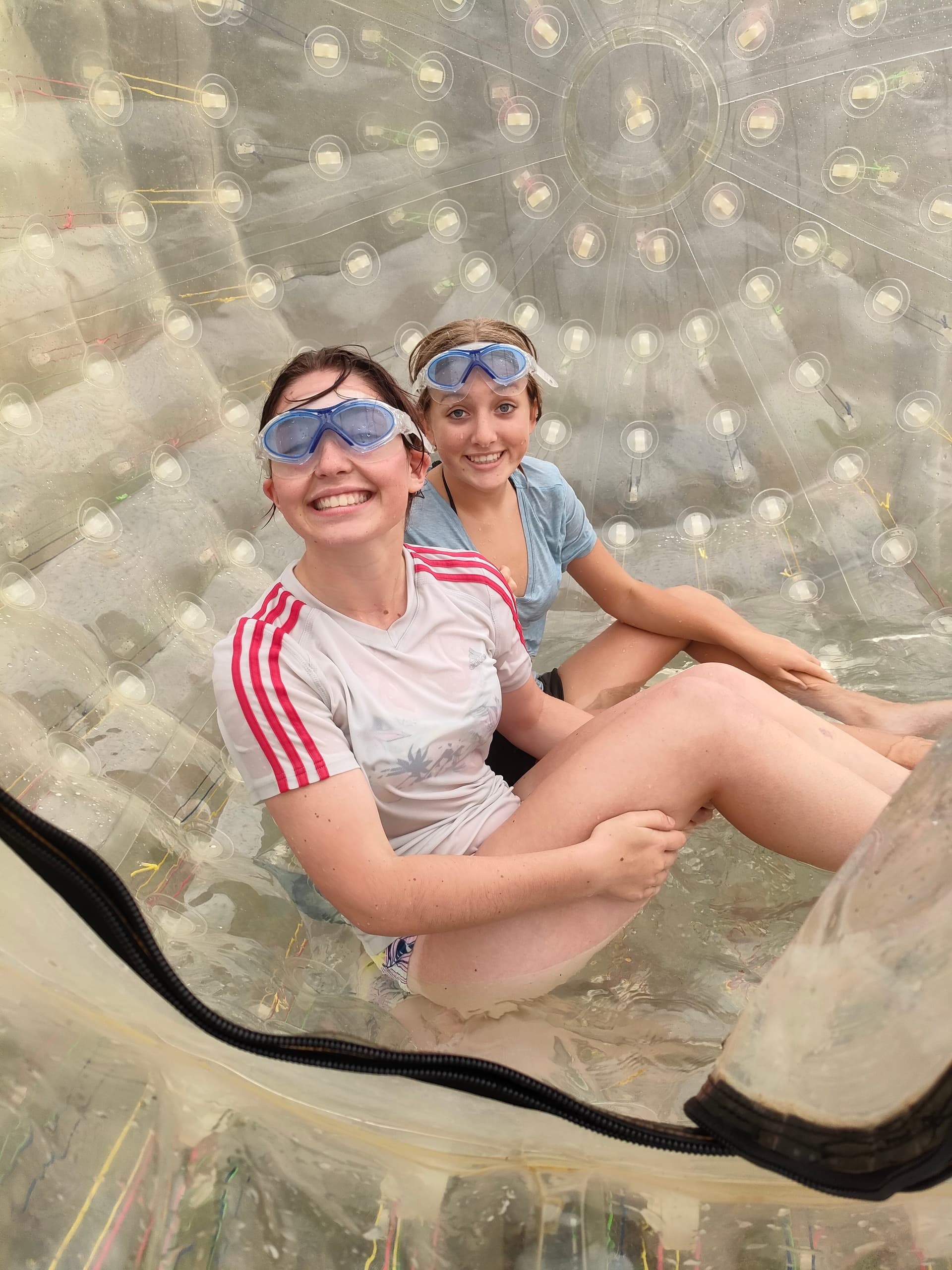 Two girls zorbing inside clear inflatable ball at adventure park