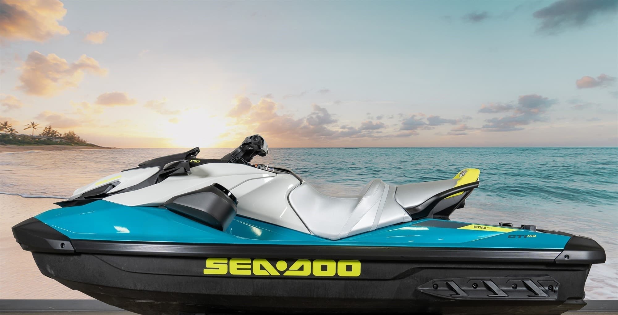 Teal Sea-Doo jet ski on sandy beach with sunrise backdrop