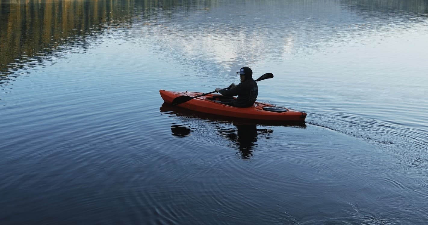 Kayaker paddling alone on reflective Potomac River at sunrise