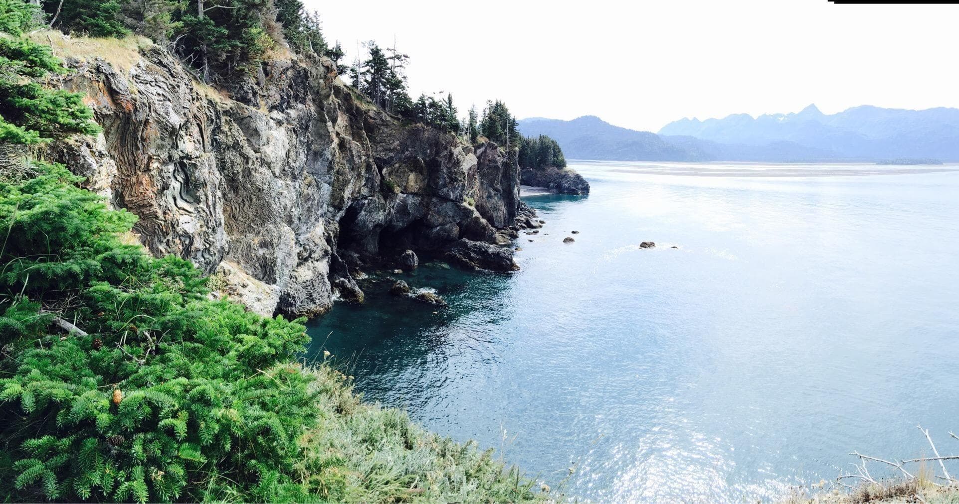 Coastal cliff viewpoint overlooking calm bay and rocky shoreline