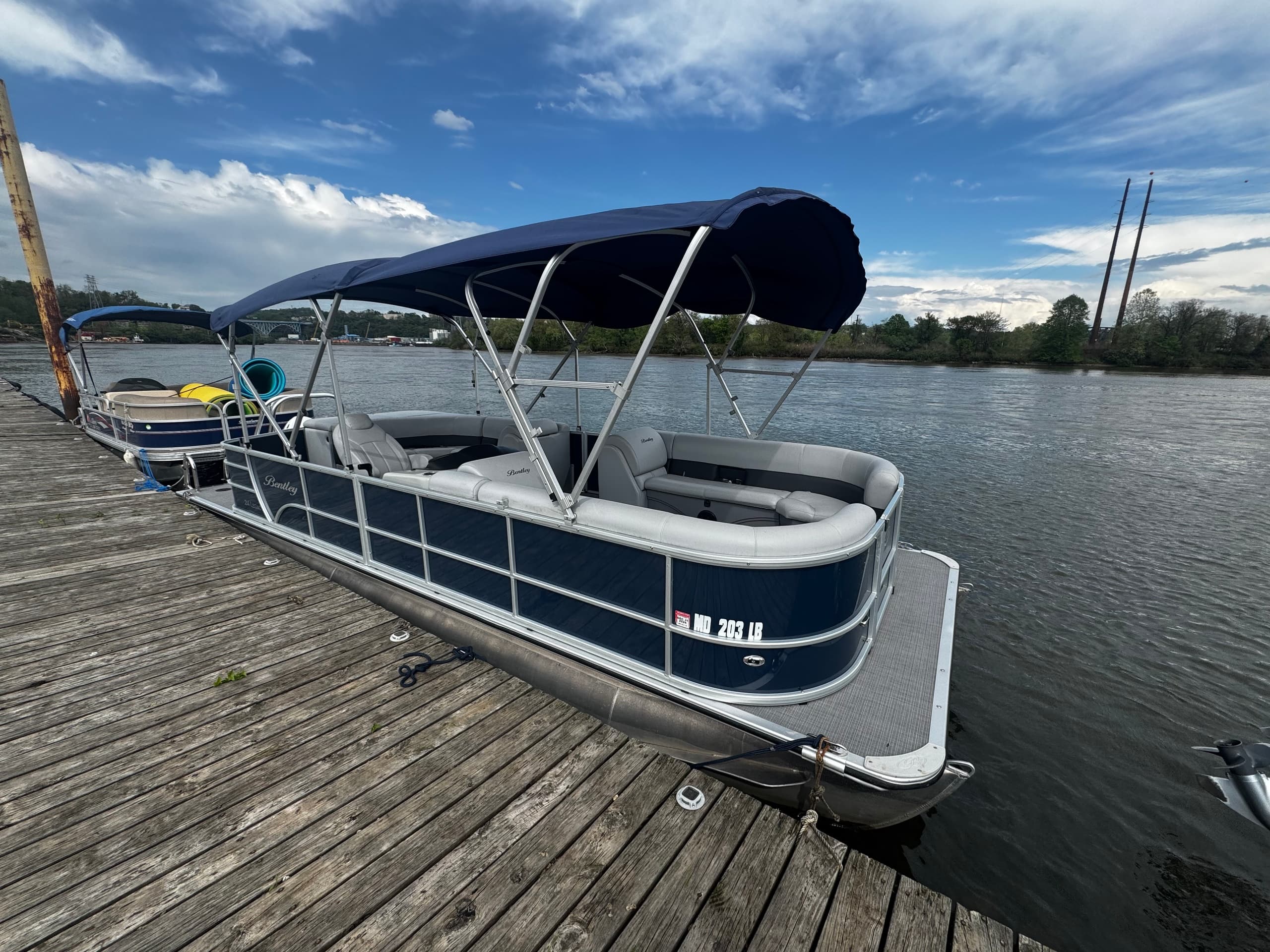 Pontoon boat docked on river with dramatic sky, lakeside rental
