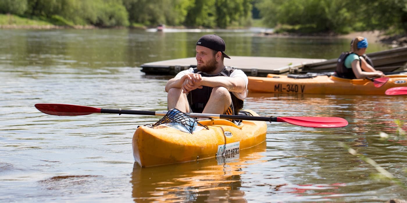 Recreational kayaker resting in calm river near other boats, summer