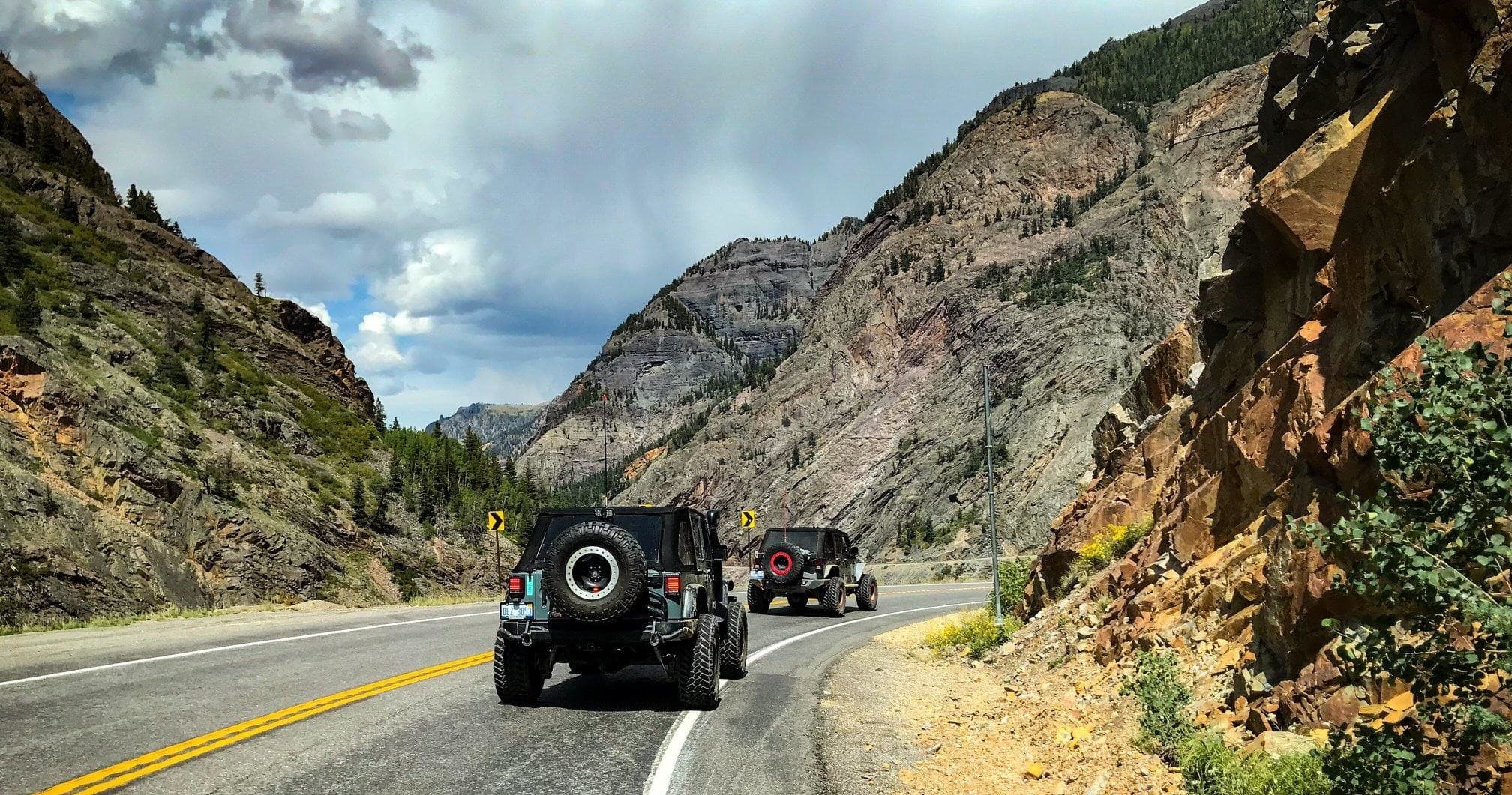 Jeep convoy driving scenic mountain highway through red canyon