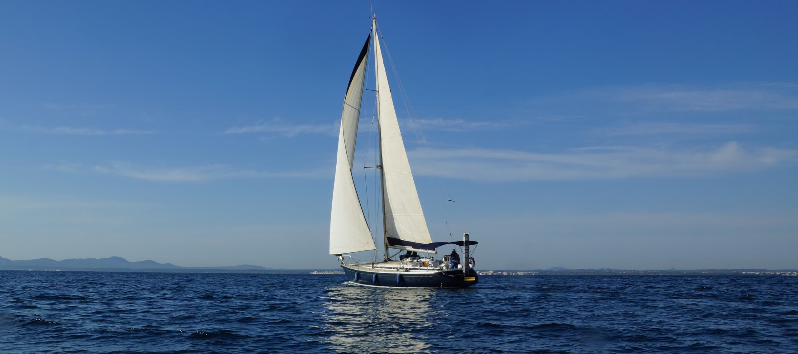 Sailboat under full sail crossing open sea on a clear day