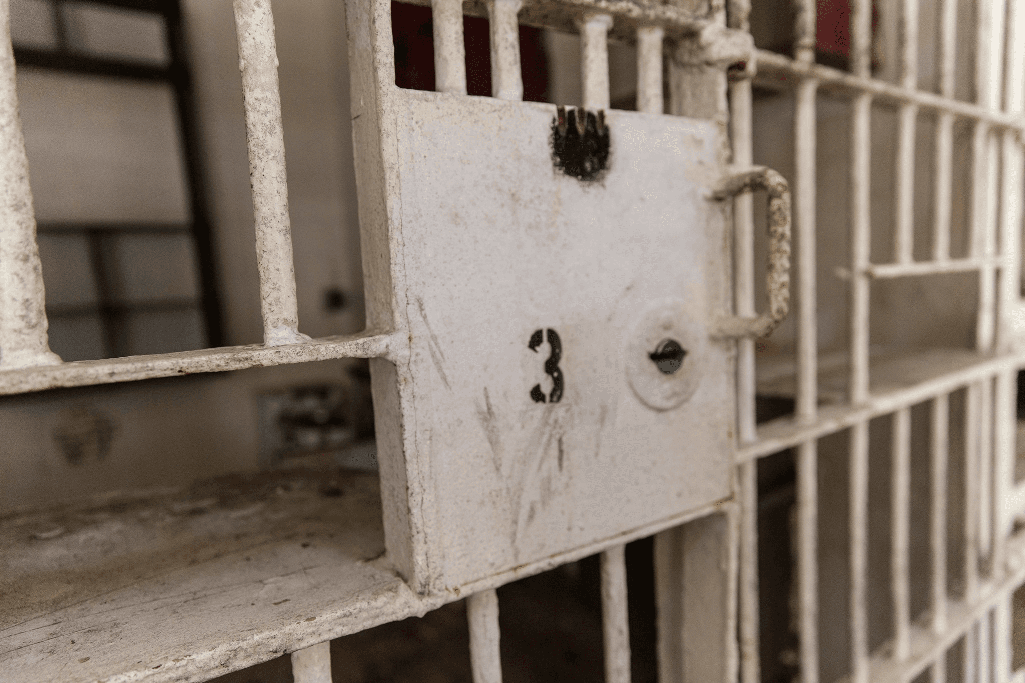 Close-up numbered cell door latch in old prison corridor, tour detail