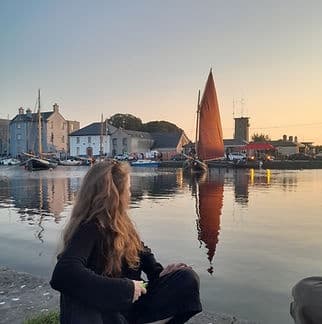Woman watching traditional sailboat at harbor sunset tour