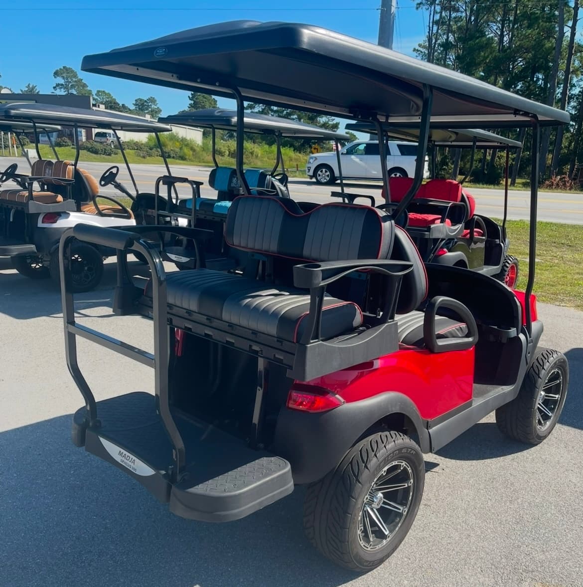 Red rear facing golf cart parked on paved lot for rental