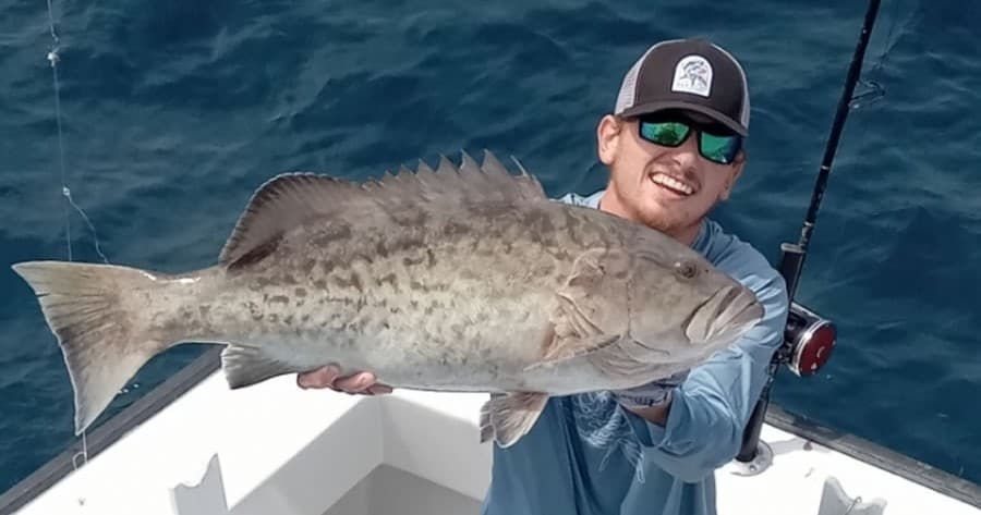 Angler holding large grouper on charter fishing trip in open ocean