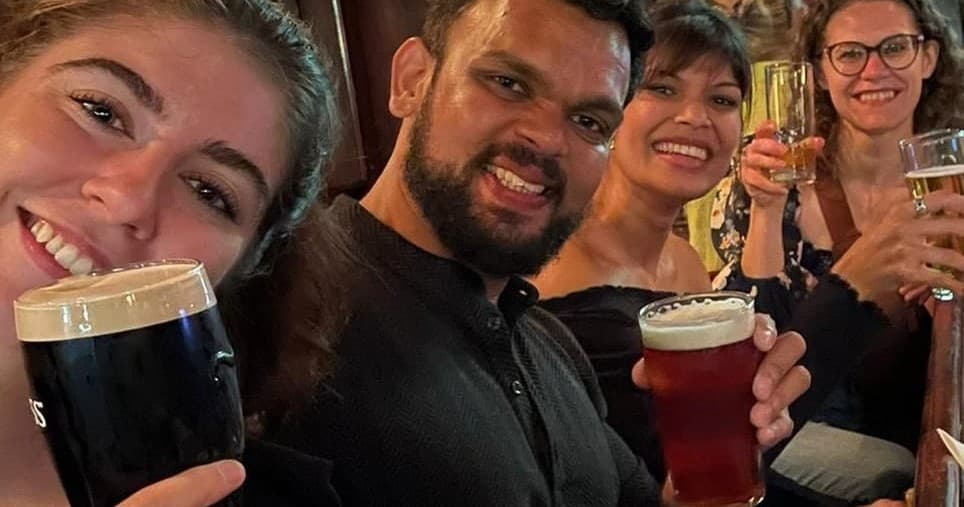 Friends taking a bar selfie holding pints of beer indoors