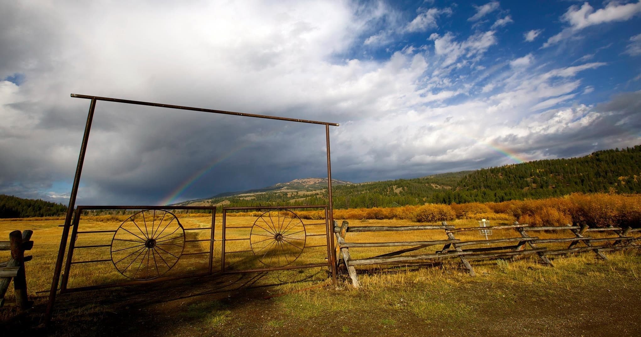 Rustic ranch gate and wagon wheels framing open pasture