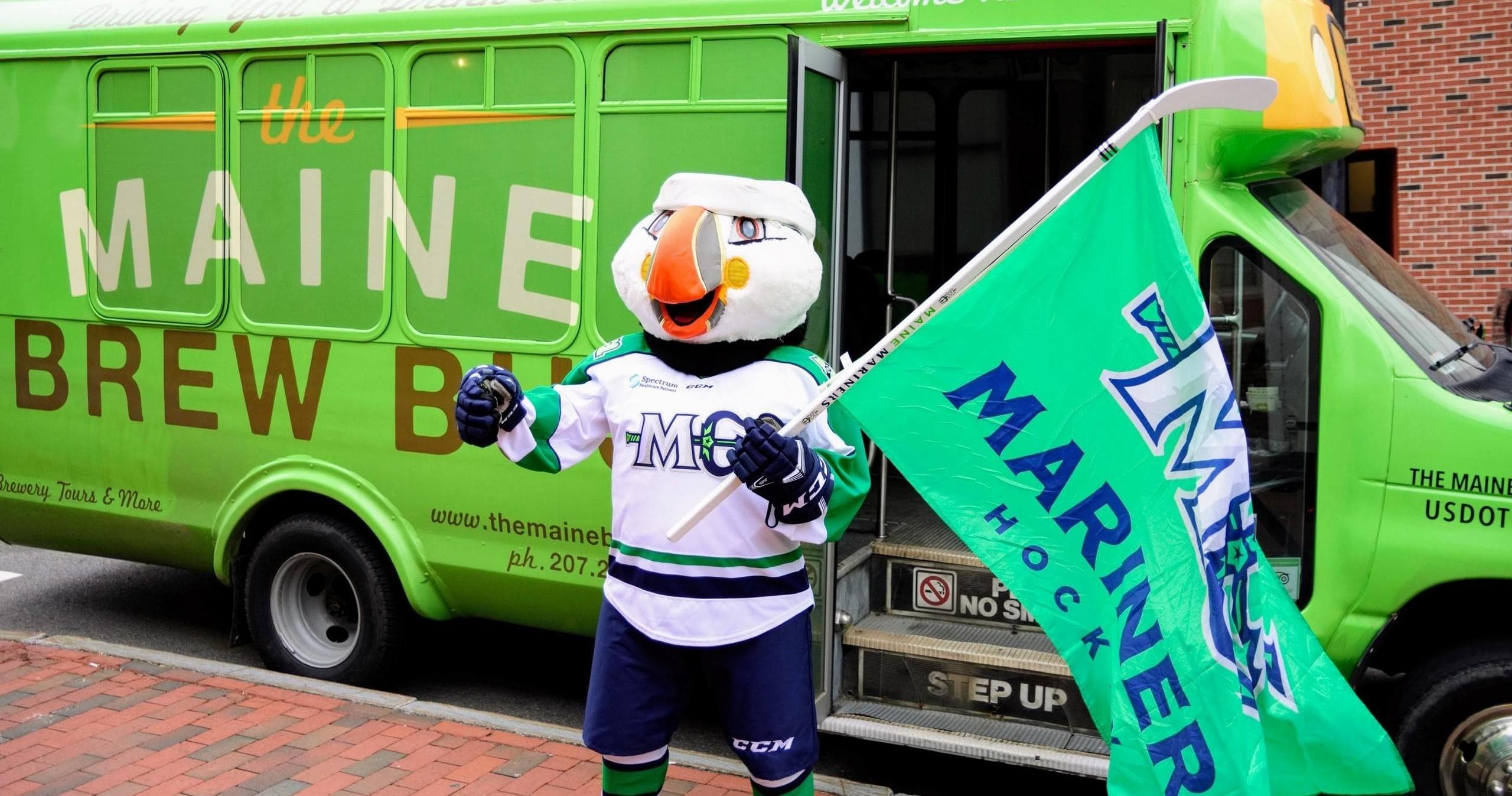 Maine Brew Bus parked near ballpark with mascot outdoors
