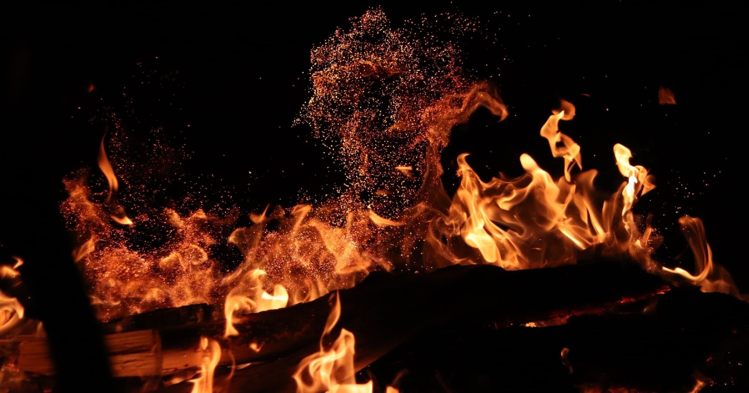 Campfire flames roaring at night during outdoor gathering