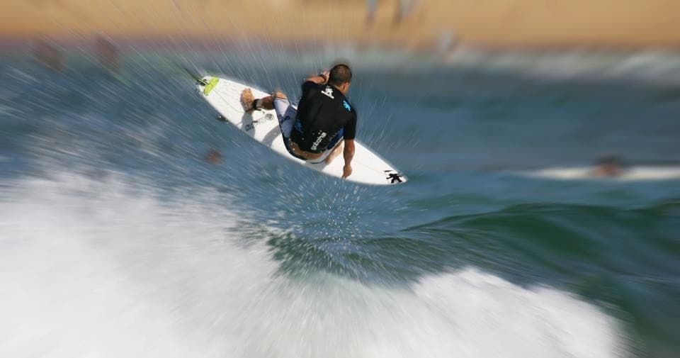 Surfer carving a wave off sandy Central Coast shoreline
