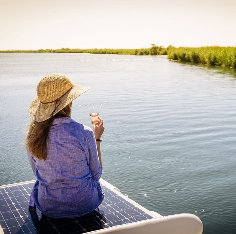 Woman relaxing on boat sipping wine on calm marsh waters