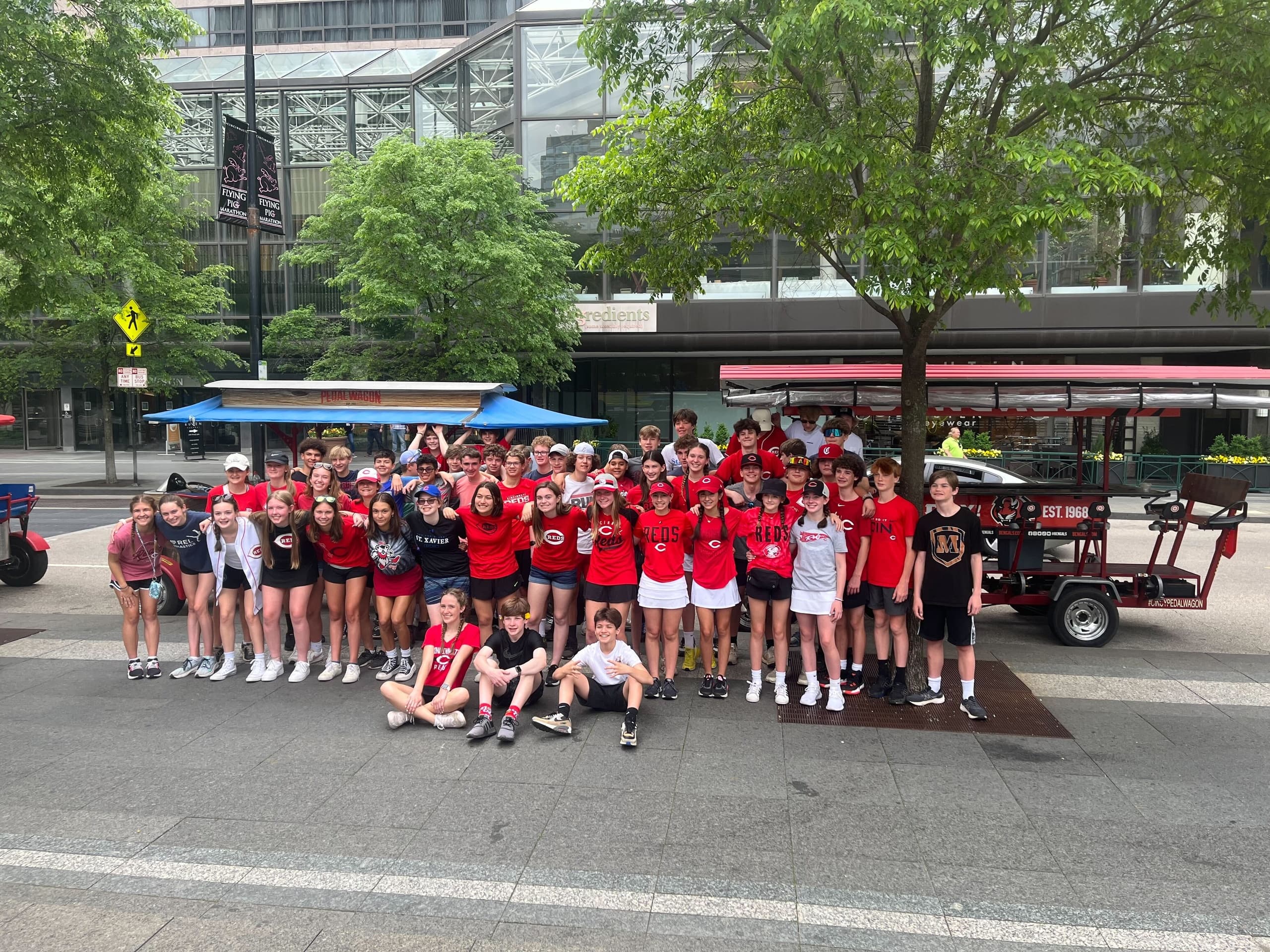 Large team posing with pedal wagon outside Cincinnati plaza