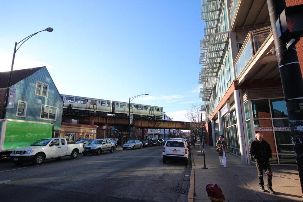 City street scene under elevated tracks with pedestrians