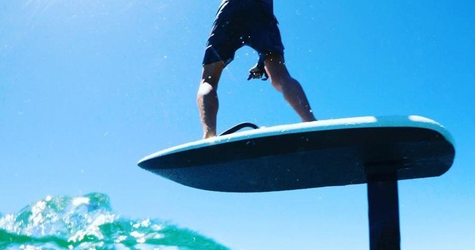 Close-up of hydrofoil surfboard lifting above turquoise ocean wave