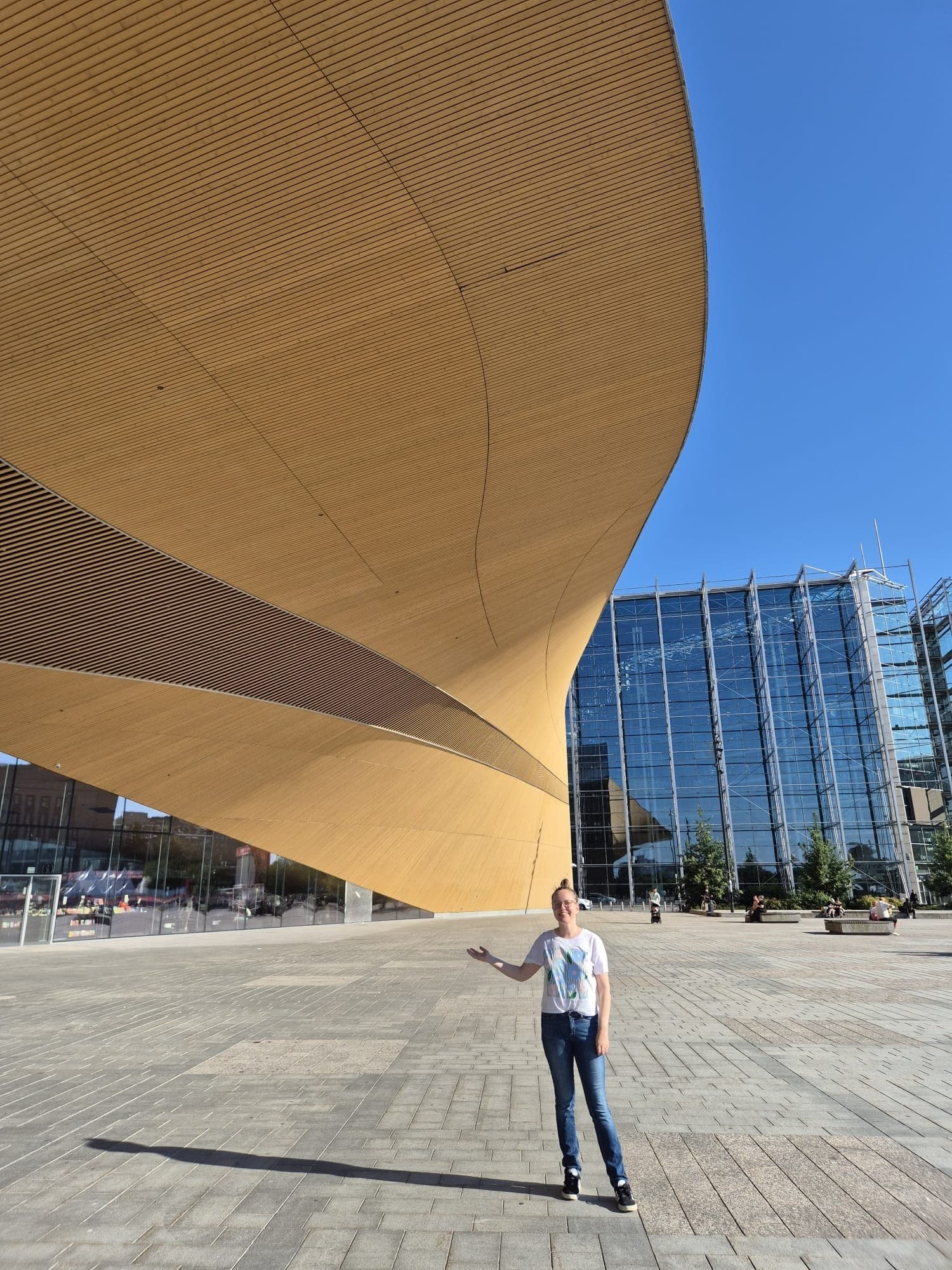 Architectural underside of Oodi library with person on plaza