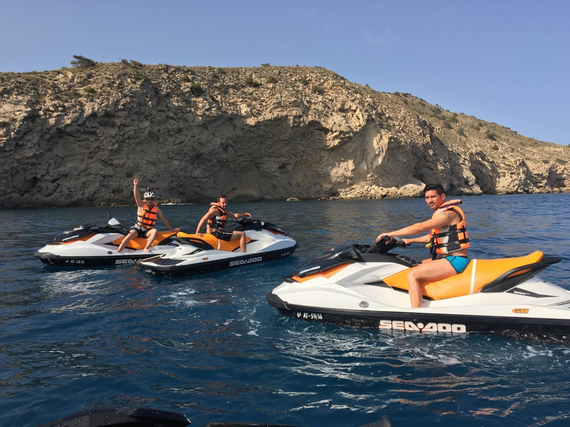 Two jet skis speeding along rocky Mediterranean coastal waters