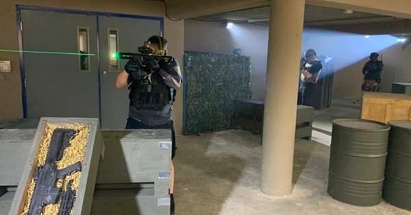 Airsoft players advancing through indoor warehouse course with cover
