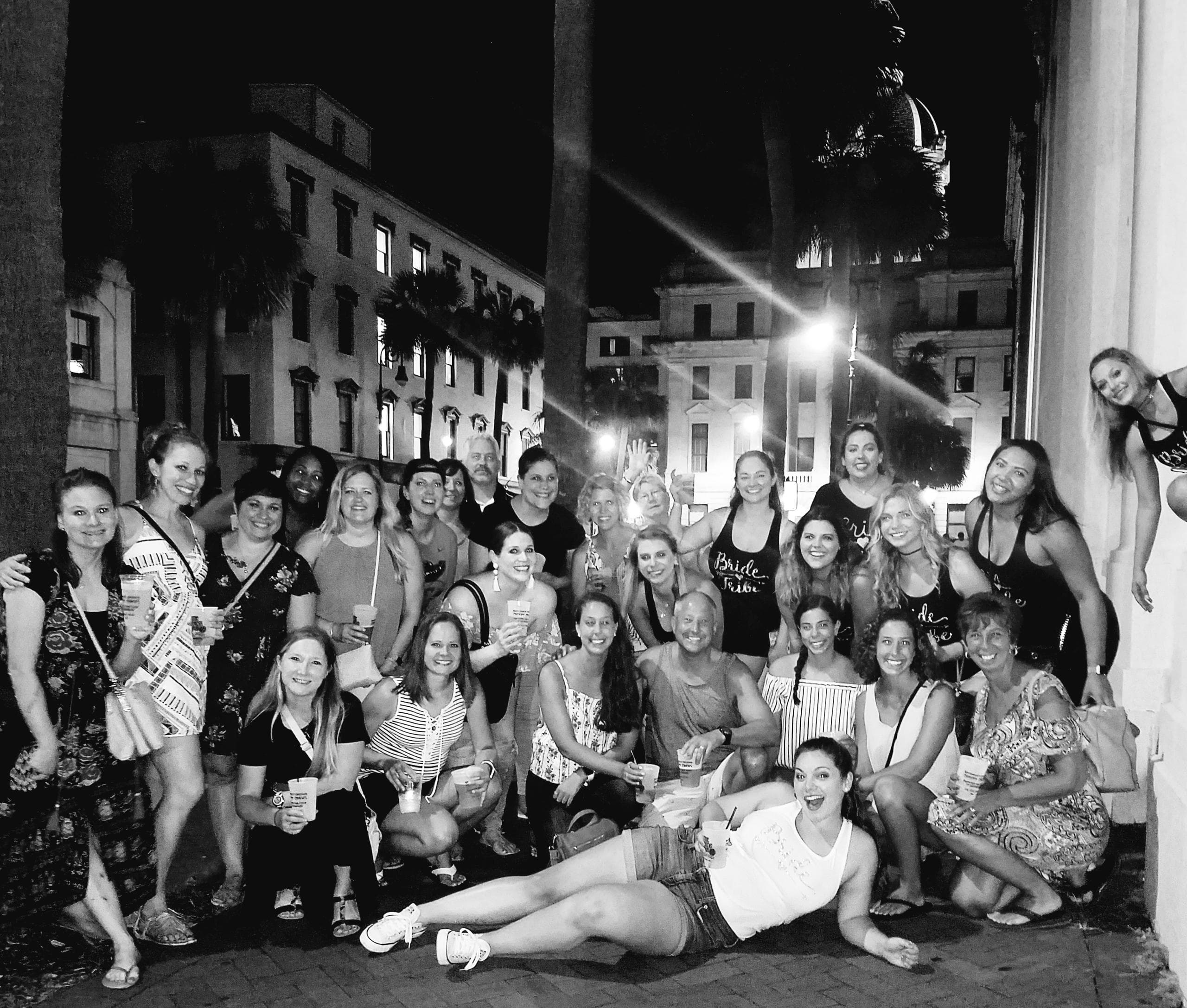 Large pub crawl group posing on historic Savannah square at night