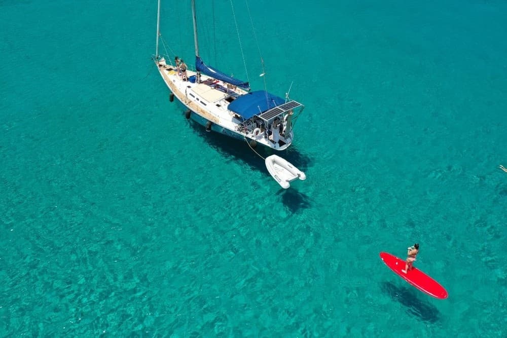 Aerial sailboat and red paddleboard on crystal turquoise sea