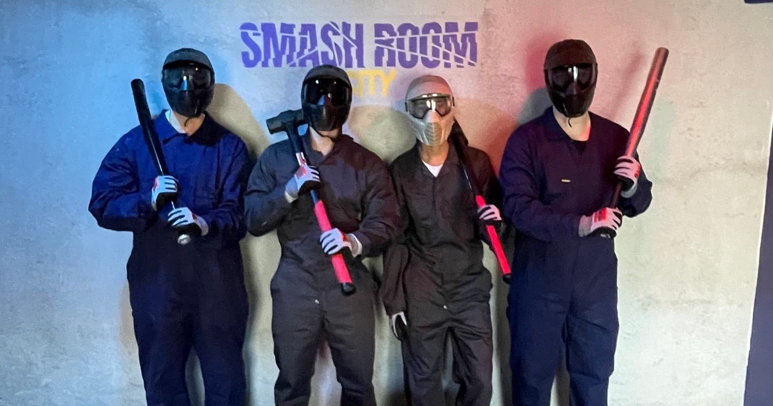 Group in protective gear smashing items in indoor rage room