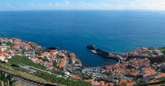 Aerial view of coastal Madeira town and harbor with blue sea