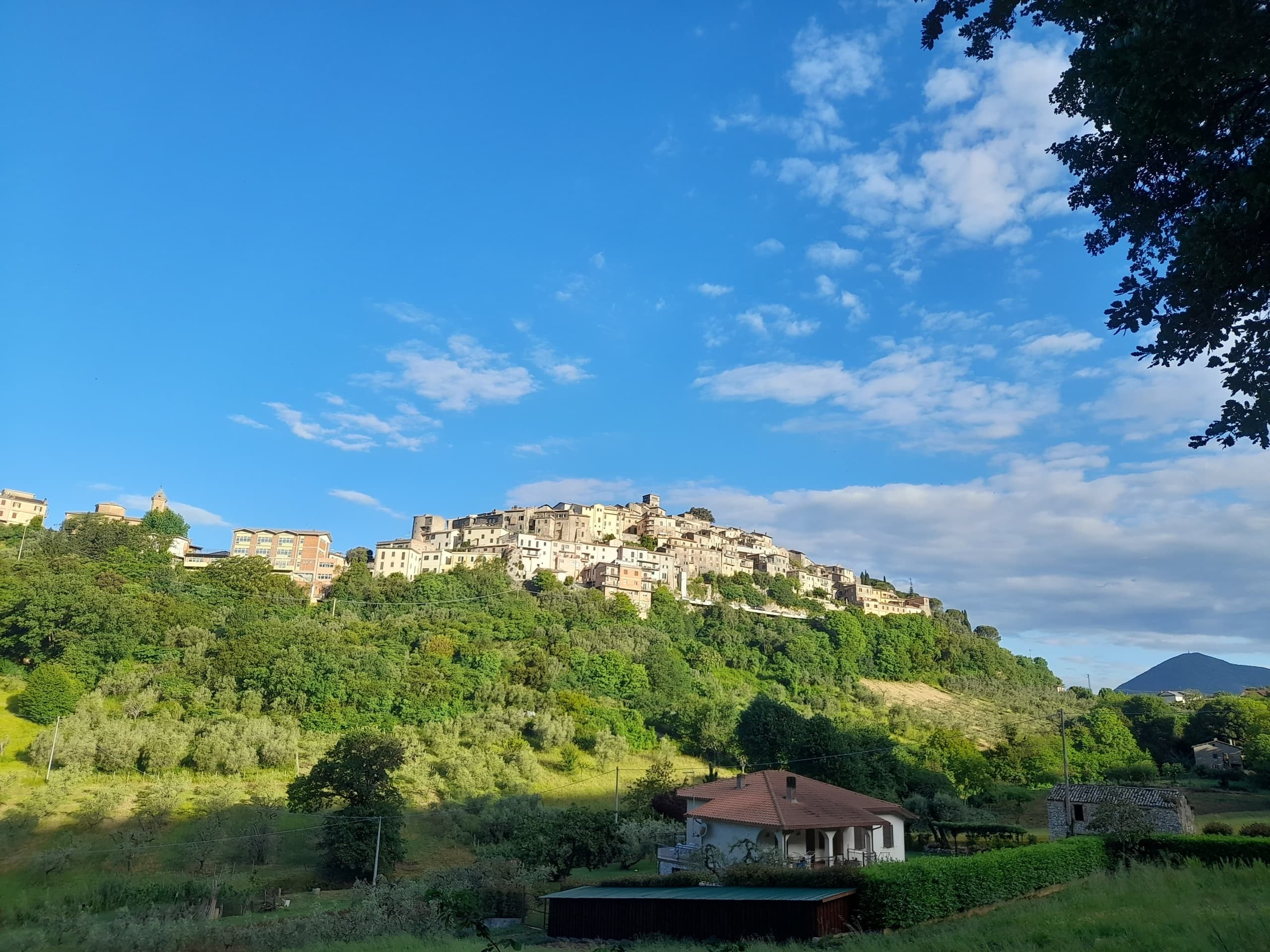 Hilltop village panoramic view over green valley at sunset