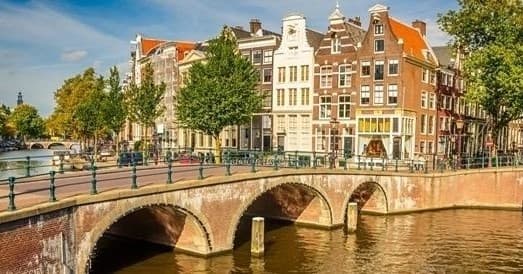 Historic Amsterdam canal with bridge, leisurely boat cruising