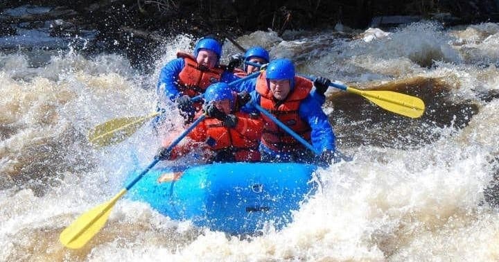 Adventurers whitewater rafting through fast-flowing river waves