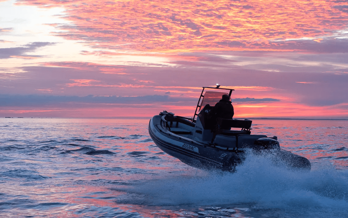 Rigid inflatable boat at sunset on choppy sea for coastal adventure