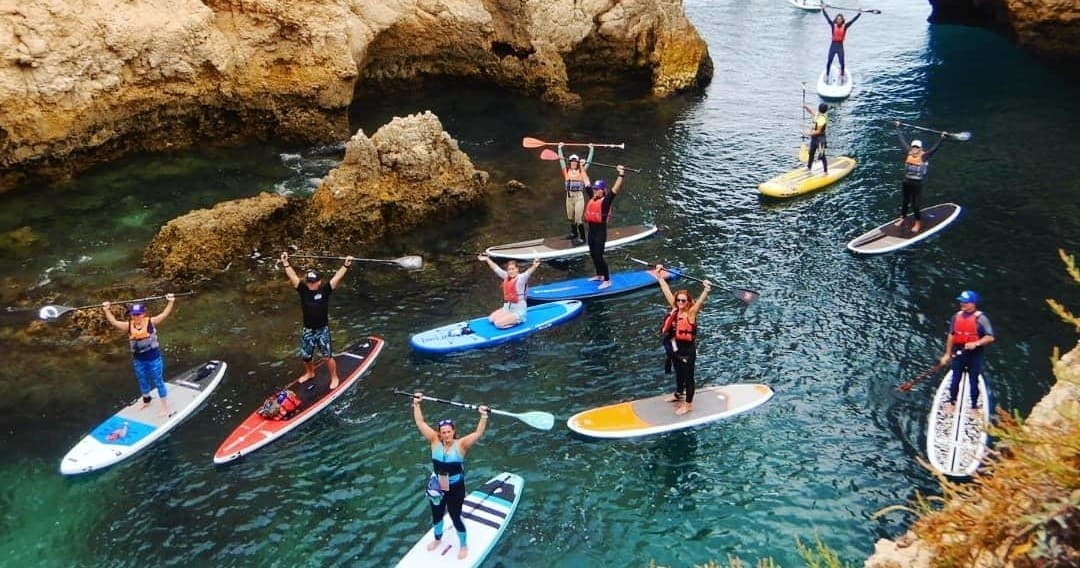 Group paddleboarding along Algarve sea cliffs on coastal tour