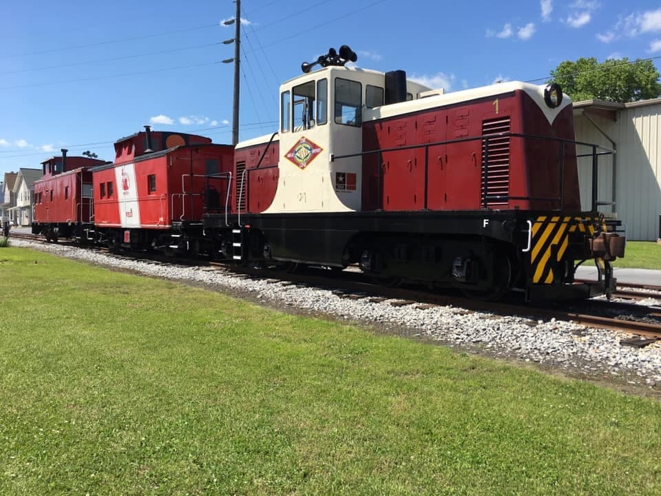 Row of vintage locomotives on display by grassy siding