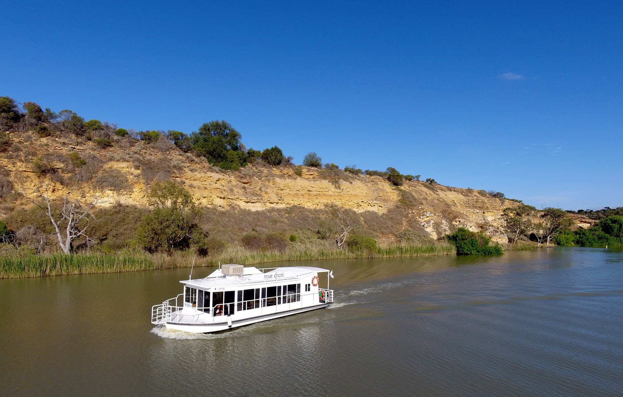 Scenic Murray River cruise boat passing river cliffs at midday