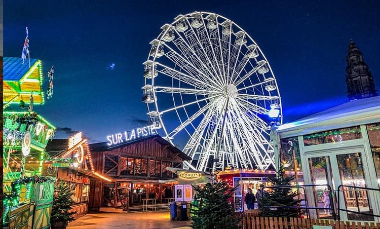 Nighttime fair with illuminated ferris wheel and rides