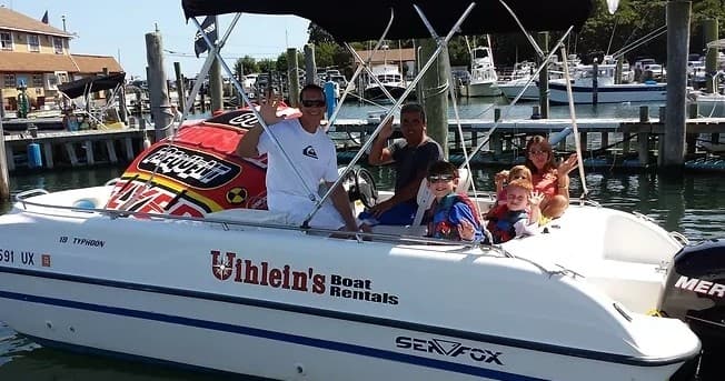Family aboard a rental powerboat at a busy marina dock